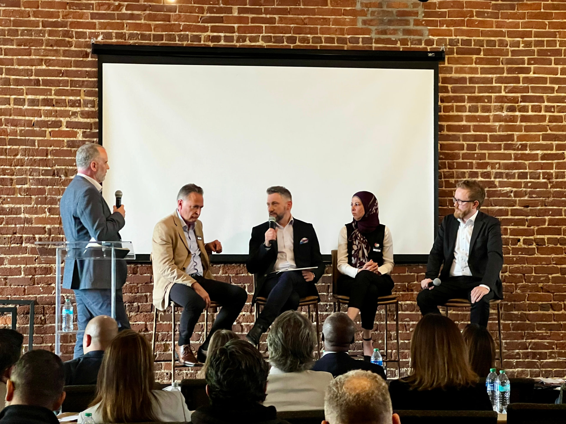 Andrew Wrobel speaking on a five-person panel at CXOutsourcers Mindshare 2024 in Atlanta, with the audience in the foreground