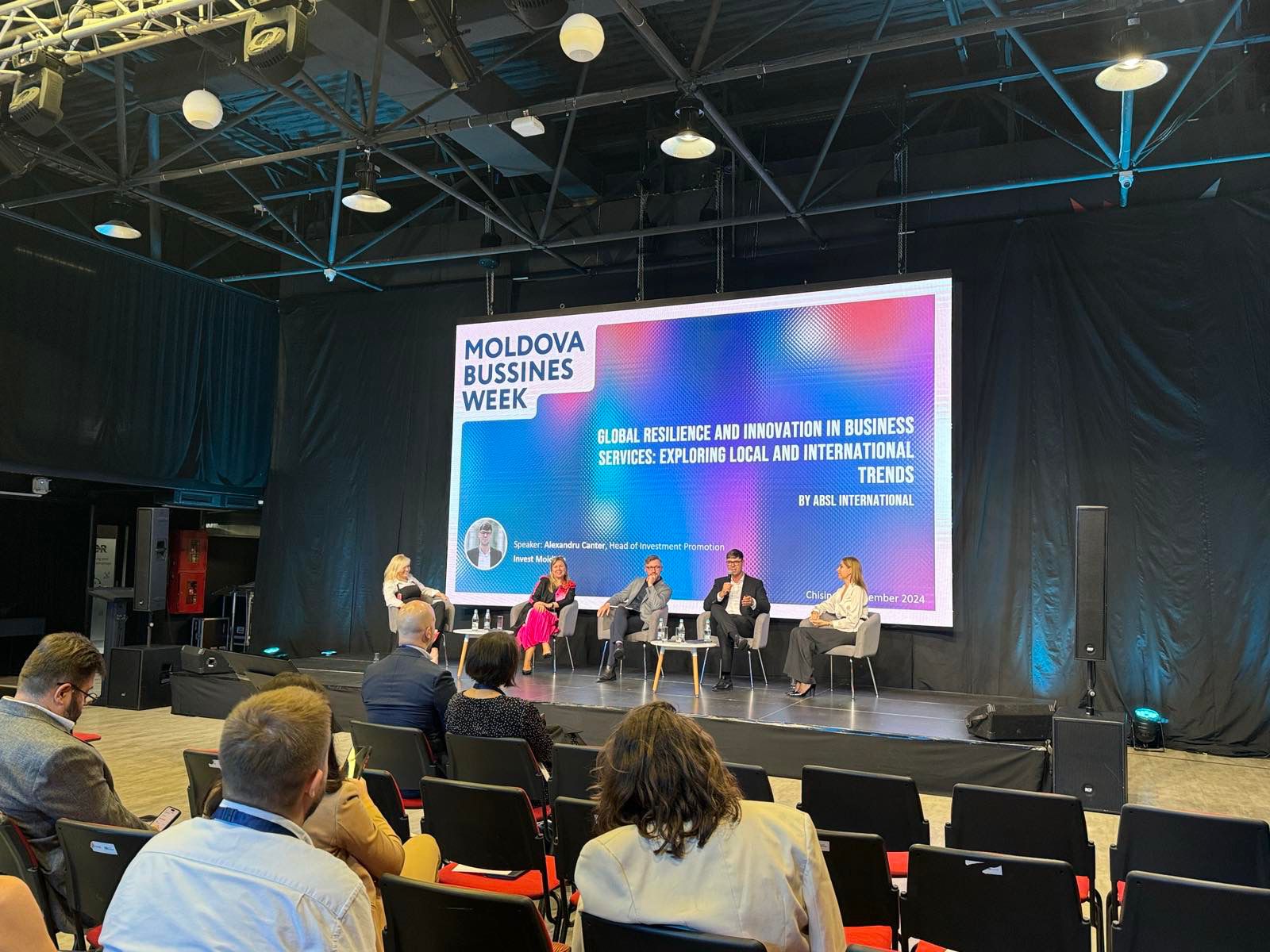 Andrew Wrobel taking part in a panel discussion at Moldova Business Week in Chișinău, with the moderator and the session title on the screen behind them