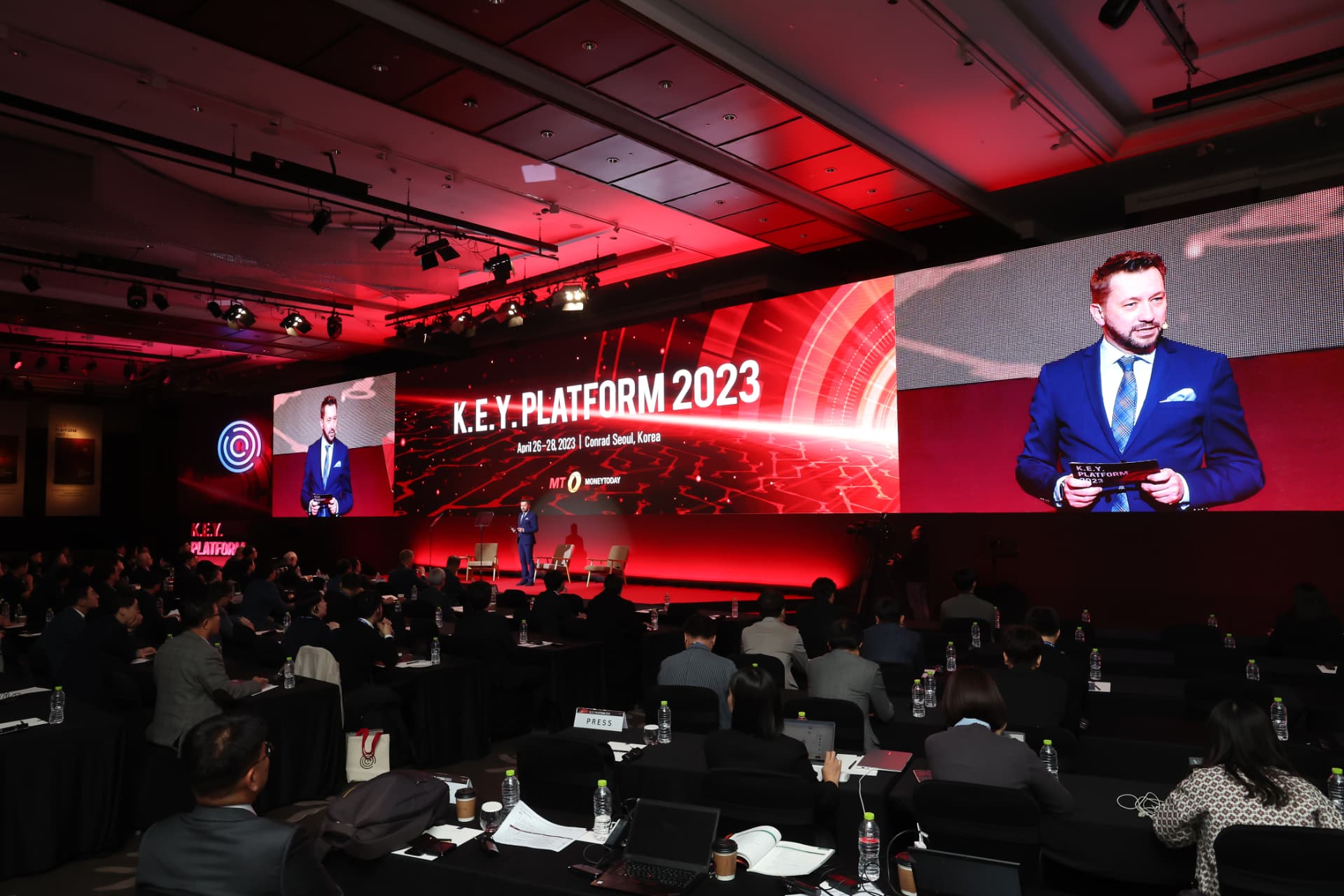 Andrew Wrobel on the wide K.E.Y. Platform 2023 stage at the Conrad Seoul, the screen behind him reading 'K.E.Y. Platform 2023, April 26–28, 2023 | Conrad Seoul, Korea' over the audience in the foreground