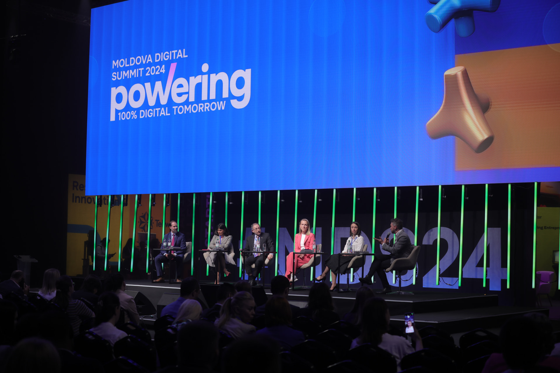Andrew Wrobel speaking into a microphone on a six-person panel at the Moldova Digital Summit 2024 in Chișinău, with the summit screen behind the stage